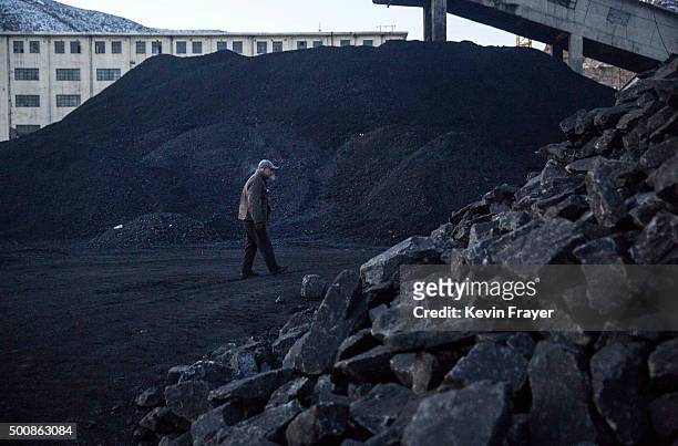 Chinese man collects coal in a sorting area at a coal mine on November 25, 2015 in Shanxi, China. A history of heavy dependence on burning coal for...