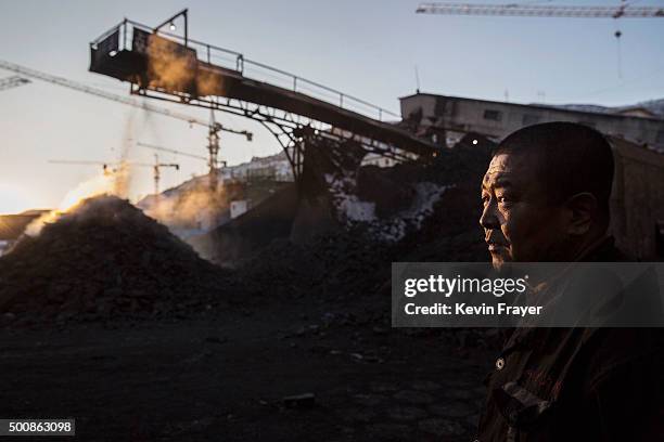 Chinese mine worker looks on as coal is moved on a conveyor belt in a sorting area at a coal mine on November 25, 2015 in Shanxi, China. A history of...