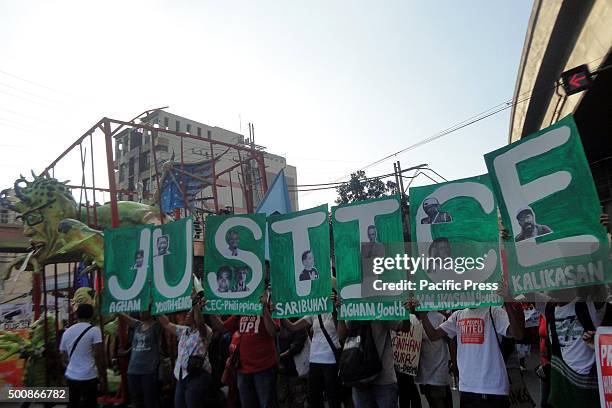 An effigy of Philippine President Benigno Aquino is seen as Filipino protesters hold placards that read the word "Justice" during a protest marking...