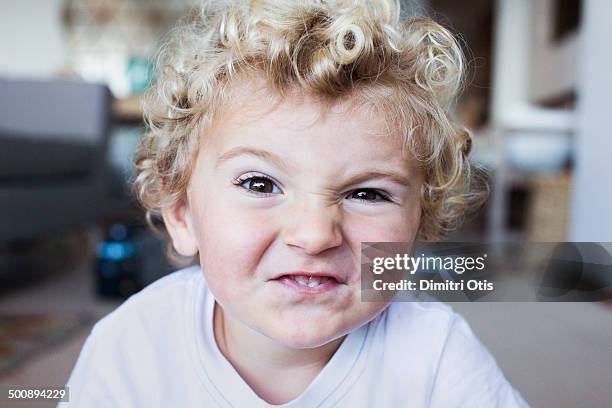 blonde toddler boy pulling fierce face - poner caras fotografías e imágenes de stock