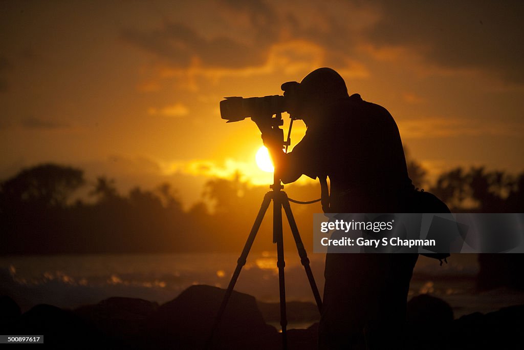 Photographer at sunset on shore of Kona, Hawaii