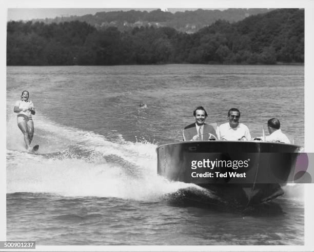 South African heart surgeon Christiaan Barnard, driving a speed boat, as his daughter Deidre water skii's, Ruislip Lido, Middlesex, June 11th 1968.