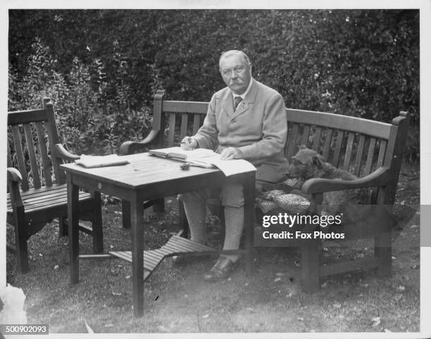 Portrait of Sir Arthur Conan Doyle sitting at a table in his garden, Bignell Wood, New Forest, 1927.