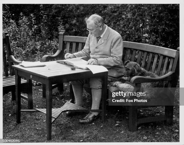 Portrait of Sir Arthur Conan Doyle sitting at a table in his garden, Bignell Wood, New Forest, 1927.