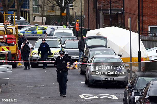 Police offciers work next to a forensics tent covering the body of a man who was shot by police officers on December 11, 2015 in Wood Green, London,...