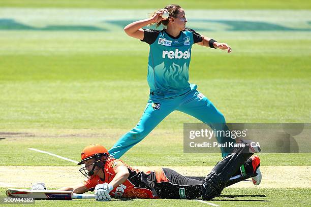 Kate Cross of the Heat looks for a run out as Katherine Brunt of the Scorchers dives to make her ground during the Women's Big Bash League match...