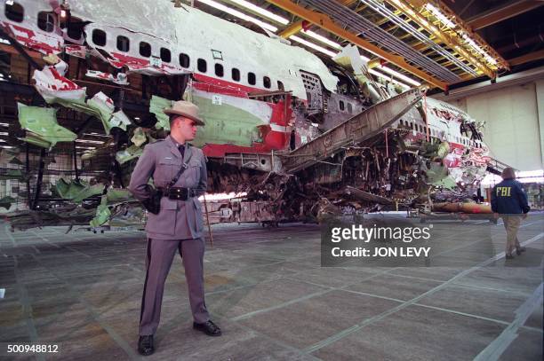 New York State trooper stands guard 19 November in front of the reconstructed wreckage of the Boeing 747 aircraft that was TWA flight 800, in...