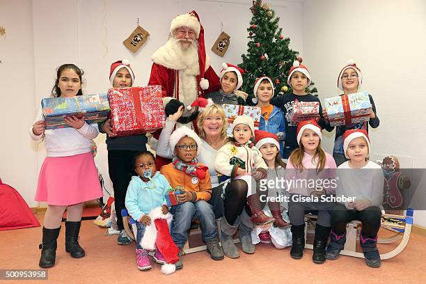 Jutta Speidel poses with a group of kids and a Santa Claus during the Christmas party at Horizont e.V. On December 11, 2015 in Munich, Germany.