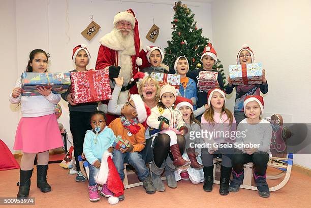 Jutta Speidel poses with a group of kids and a Santa Claus during the Christmas party at Horizont e.V. On December 11, 2015 in Munich, Germany.