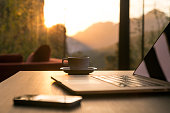 Computer Coffee Mug Telephone on black wood table sun rising