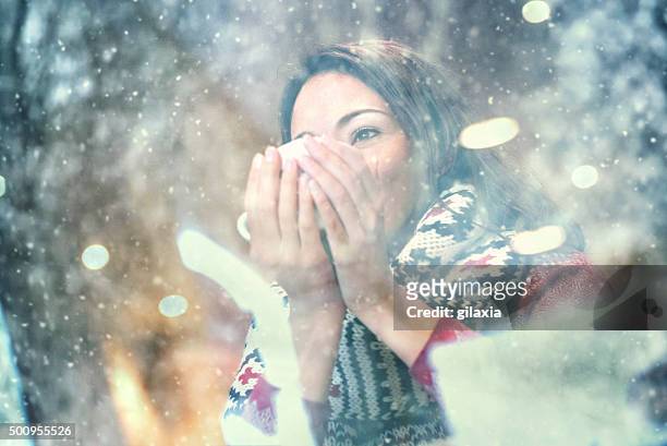 woman having a tea or coffee on snowy day. - photographed through window stockfoto's en -beelden