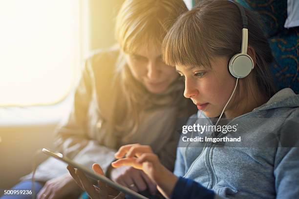 ragazza con madre in viaggio in treno e suona su tablet - bambino treno foto e immagini stock