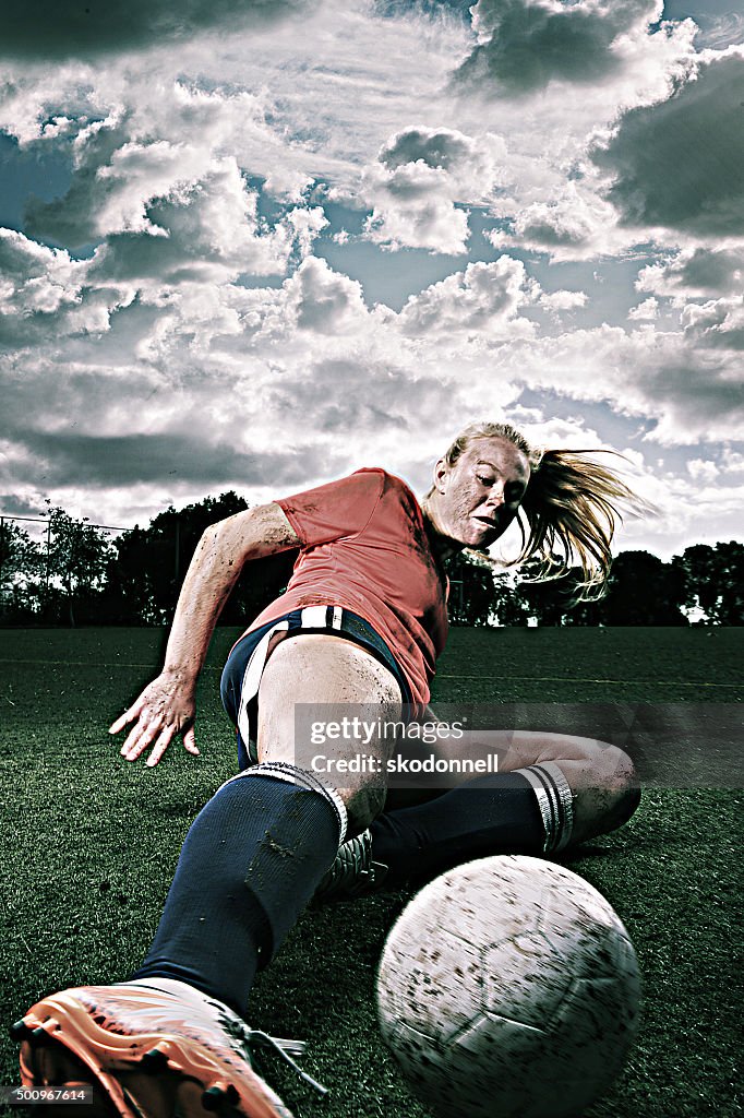 Dirty Female Soccer Player Sliding for the Ball
