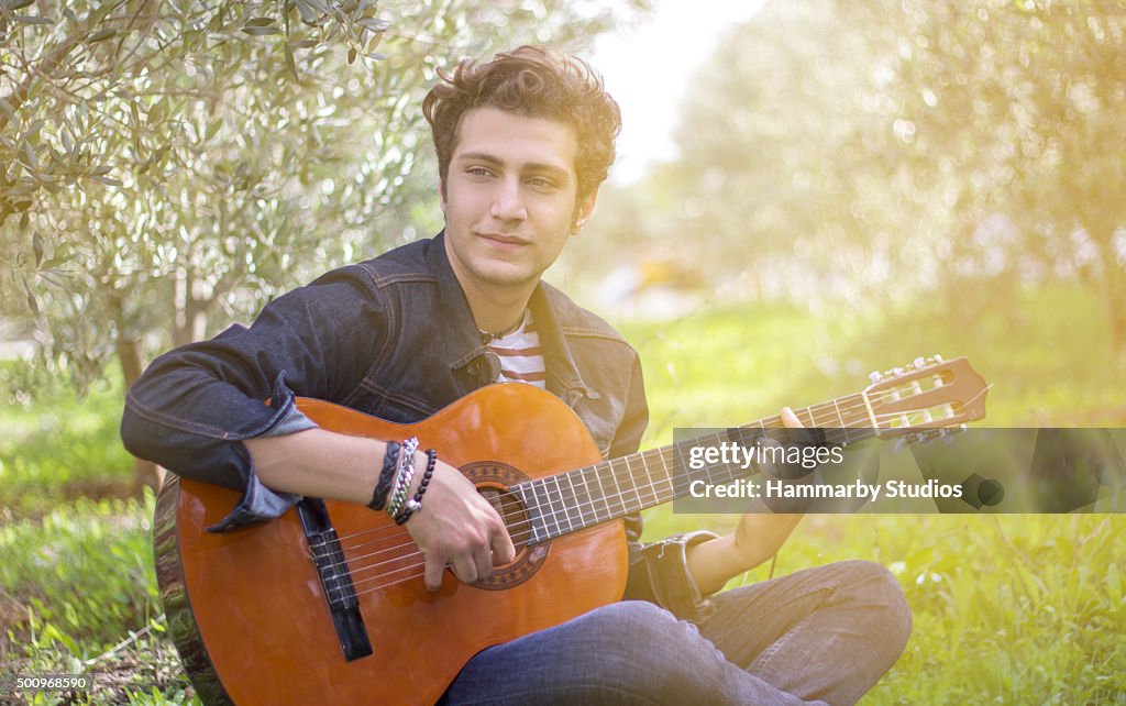 Portrait de jeune garçon jouant de la guitare dans la nature