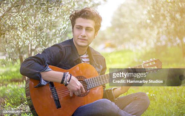 portrait of teenage boy playing guitar in nature - pop musician stock pictures, royalty-free photos & images