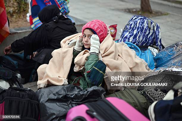 An Afghani girl sits by her family's belongings as refugees and migrants camp on December 11, 2015 at the Victoria square in central Athens. Prime...