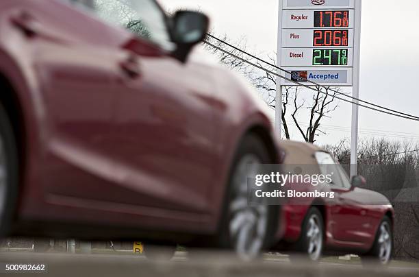 Cars drive past gas prices displayed on a sign outside a fueling station in Chilicothe, Illinois, U.S., on Friday, Dec. 11, 2015. The cost of a...