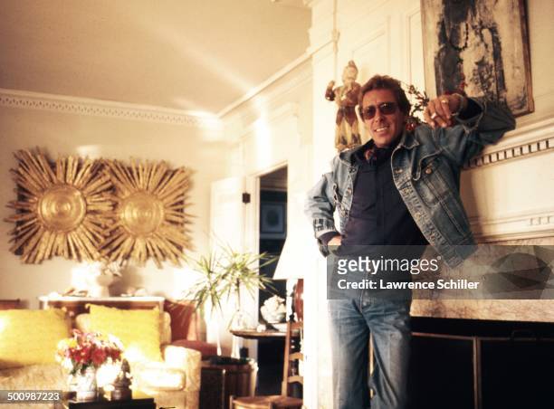 Portrait of British photographer Antony Armstrong-Jones, 1st Earl of Snowdon , a cigarette in his hand, as he leans on a fireplace mantel, 1974.