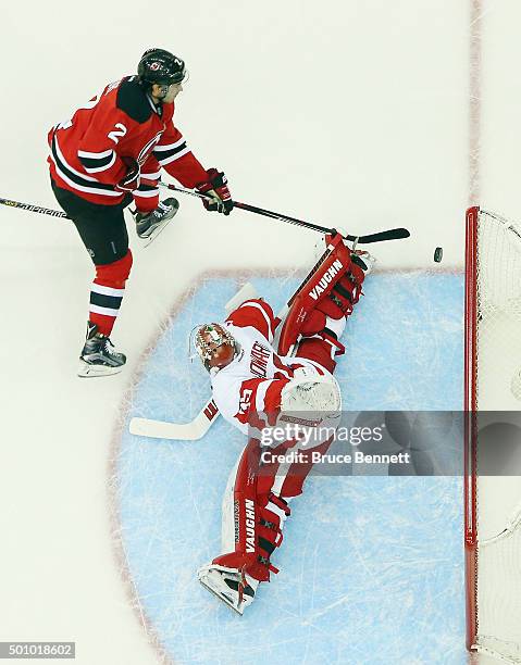 Jimmy Howard of the Detroit Red Wings makes the save on John Moore of the New Jersey Devils at the Prudential Center on December 11, 2015 in Newark,...