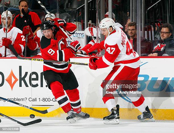 Jiri Tlusty of the New Jersey Devils and Alexey Marchenko of the Detroit Red Wings battle a loose puck during the game at the Prudential Center on...
