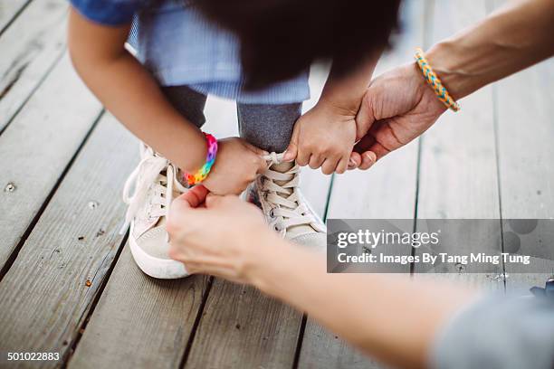 mom teaching little girl to tide her shoelace - family shoes stock-fotos und bilder