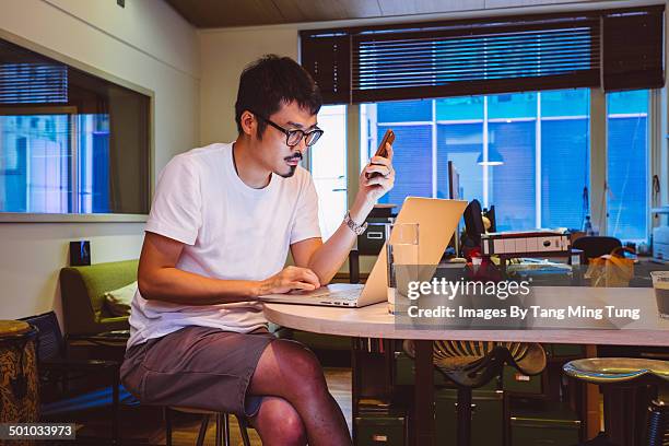 young man working with laptop in home office - shorts stockfoto's en -beelden