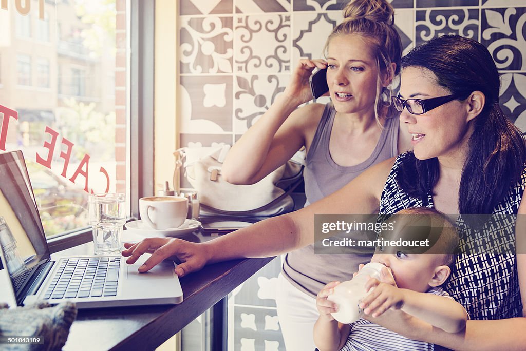 Urban mom balancing work and family with colleague in cafe.