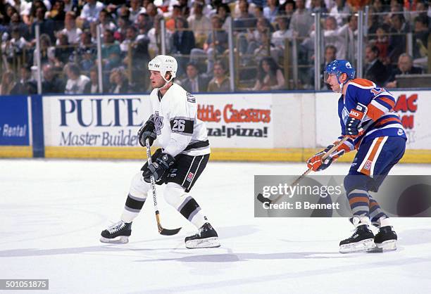 Mike Krushelnyski of the Los Angeles Kings skates on the ice as Jari Kurri of the Edmonton Oilers follows behind circa 1989 at the Great Western...