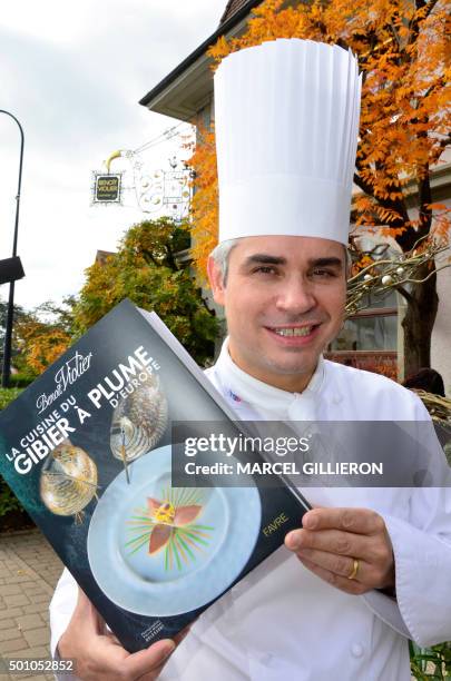 Picture taken on October 9, 2015 shows Benoit Violier, chef of the Restaurant de l'Hôtel de Ville, posing with his book 'La cuisine du gibier à plume...