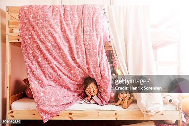 2 sisters looking out from their bed - bunk beds for 3 stock-fotos und bilder