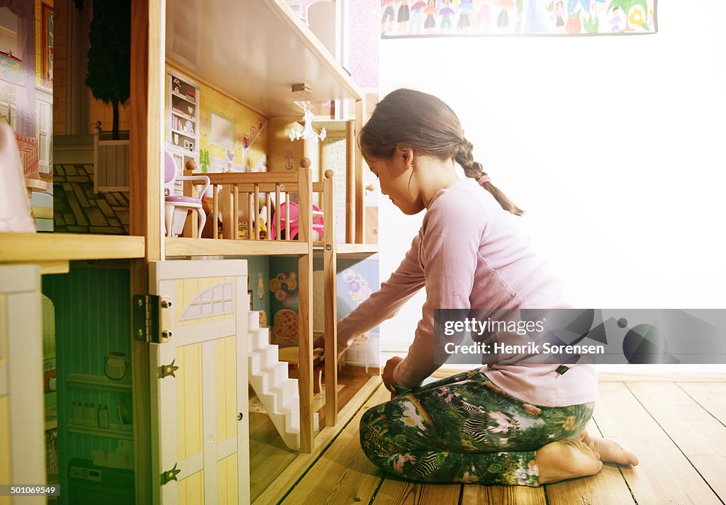 Young girl playing with dollhouse