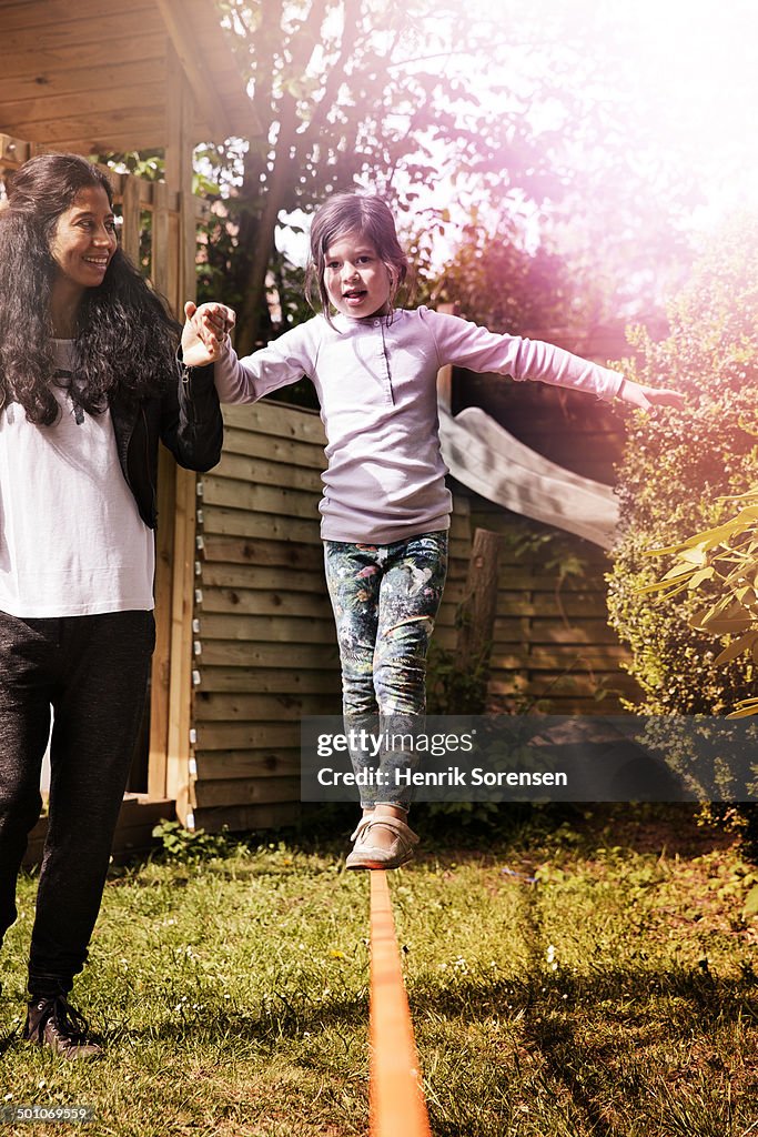 Mother supporting her daughter balancing