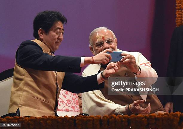 Japan's Prime Minister Shinzo Abe and India's Prime Minister Narendra Modi take a photo together on a mobile phone during the evening 'Aarti' ritual...