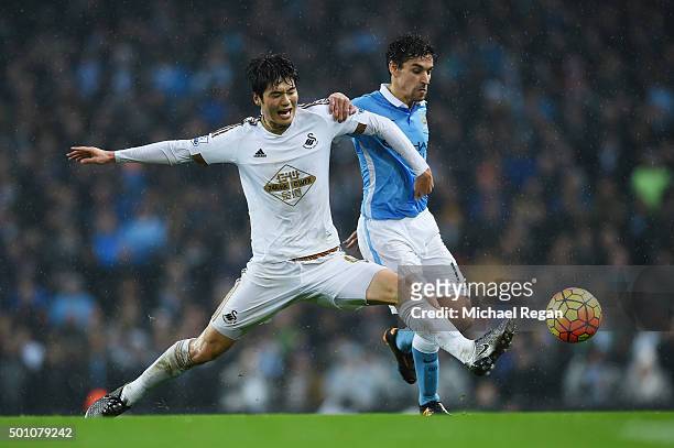 Jesus Navas of Manchester City and Ki Sung-Yeung of Swansea City compete for the ball during the Barclays Premier League match between Manchester...