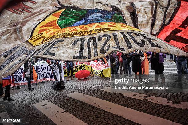Activists hold up a giant banner reading 'Climate justice' by association 'our power campaign' during a demonstration near the Arc de Triomphe at the...