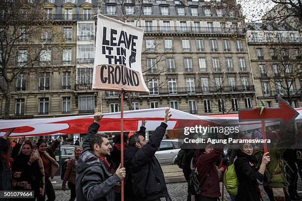 An activist holds up a poster during a demonstration near the Arc de Triomphe at the Avenue de la Grande Armee boulevard on December 12, 2015 in...