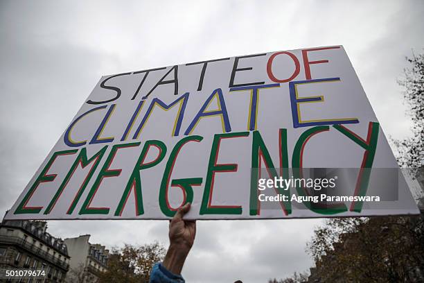 An activist holds up a poster during a demonstration near the Arc de Triomphe at the Avenue de la Grande Armee boulevard on December 12, 2015 in...
