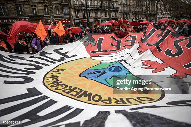 Activists hold up a giant banner reading 'Climate justice' by association 'our power campaign' during a demonstration near the Arc de Triomphe at the...