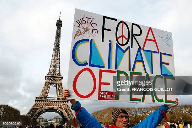 Jean-Baptiste Redde aka Voltuan holds a banner reading "For a climate of peace" during a rally held by several Non Governmental Organisations to form...