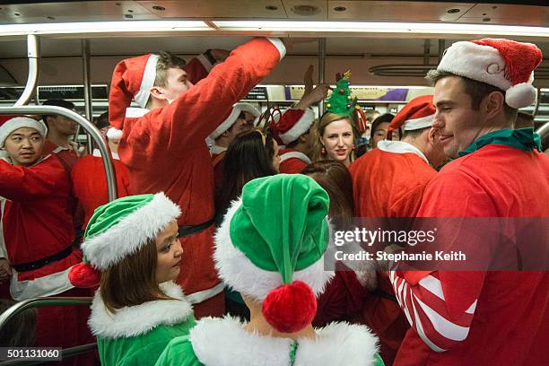 People dressed as Santas board a crowded subway during the annual SantaCon pub crawl December 12, 2015 in the Brooklyn borough of New York City....