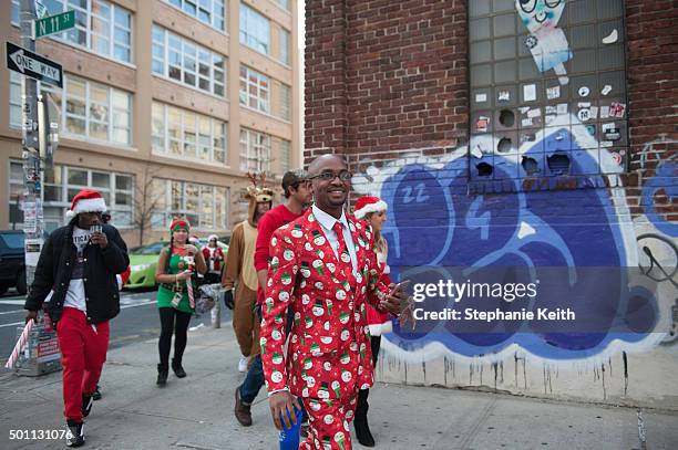 People dressed in holiday garb walk through the streets of Williamsburg during the annual SantaCon pub crawl December 12, 2015 in the Brooklyn...