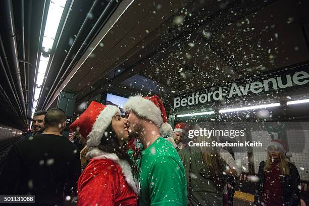 Two people dressed as a Santa share a kiss on the subway platform during the annual SantaCon pub crawl December 12, 2015 in the Brooklyn borough of...