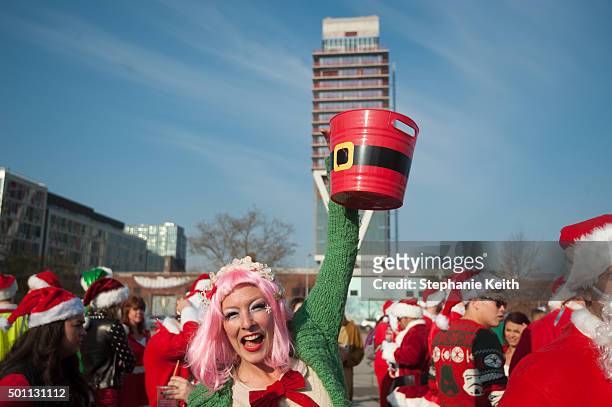 Woman dressed as a Santa's elf collects donations before the start of the annual SantaCon pub crawl December 12, 2015 in the Brooklyn borough of New...