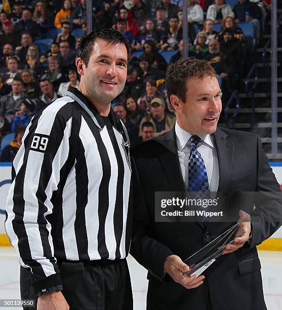 Linesman Steve Miller receives an award from NHL Director of Officiating Stephen Walkom prior to working his 1000th NHL game between the Buffalo...