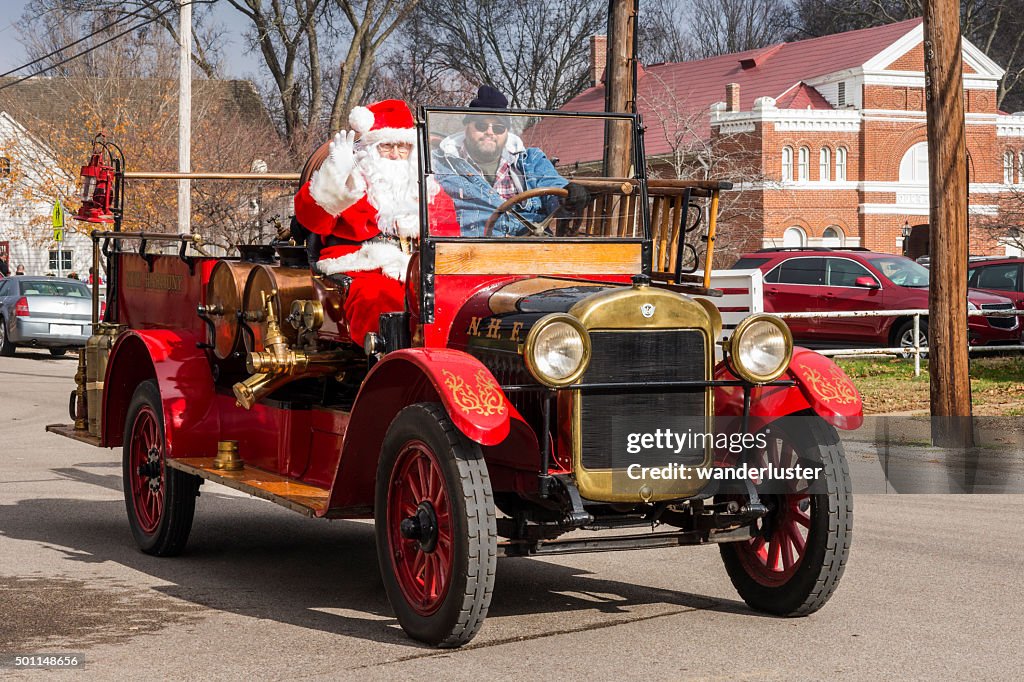 Santa waves from a vintage firetruck
