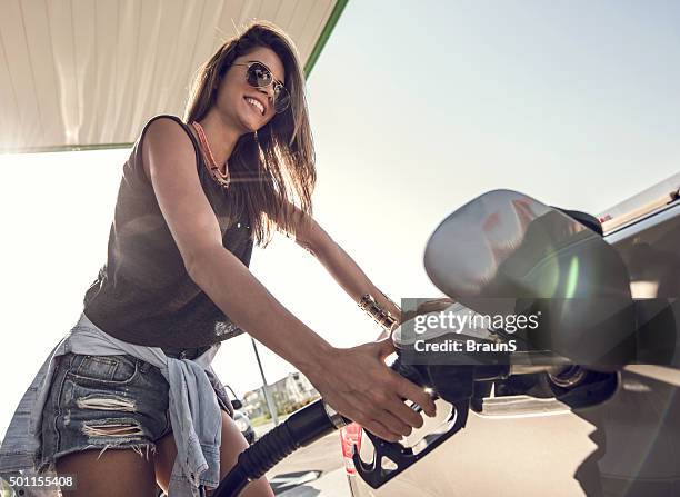 happy woman refueling the gas tank at fuel pump. - bensinstation bildbanksfoton och bilder