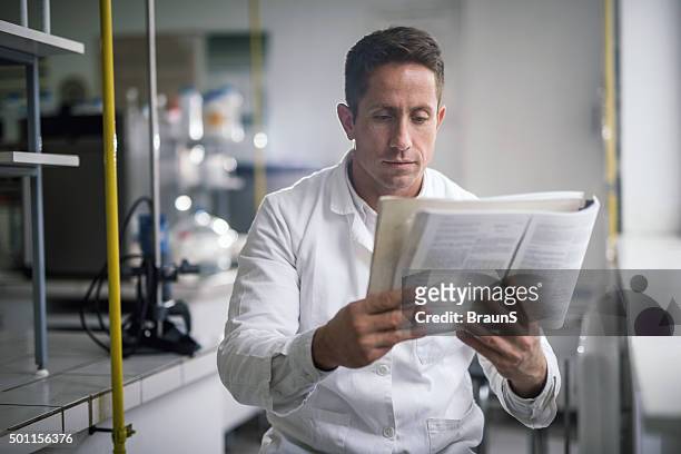 männliche chemiker lesung wissenschaftlichen daten von einem buch. - artikel publikation stock-fotos und bilder