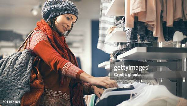 woman buying clothes at department store. - garment rack stock pictures, royalty-free photos & images