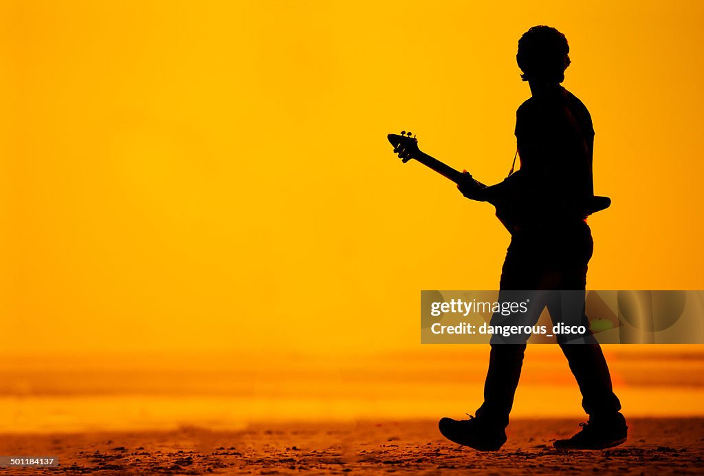 Silhouette of a man on a beach with guitar