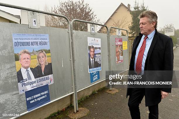 Front National far-right party top candidate for the regional elections in the Centre region Philippe Loiseau walks past electoral campaign posters...